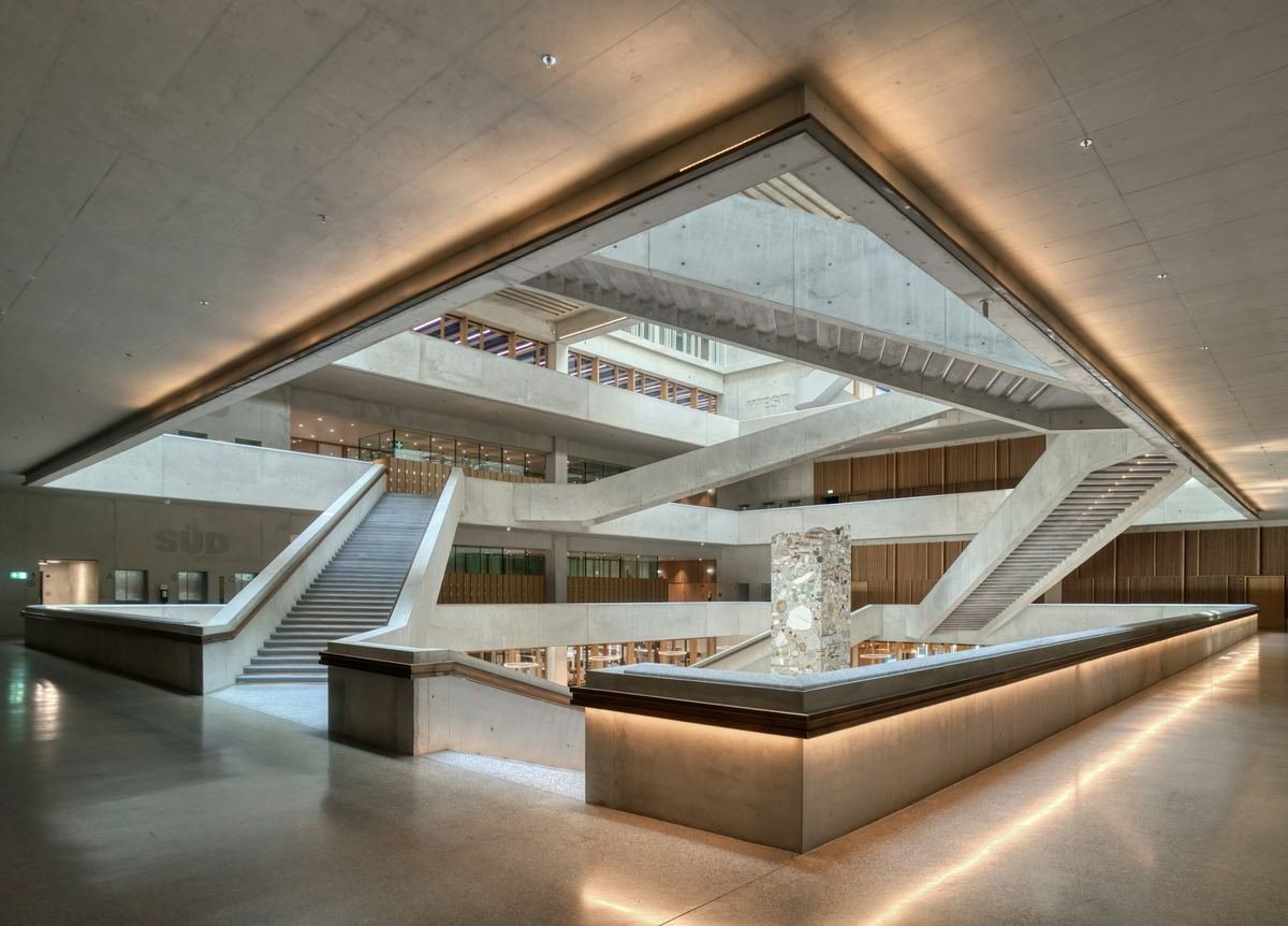 A modern atrium with a sweeping staircase and warm light.