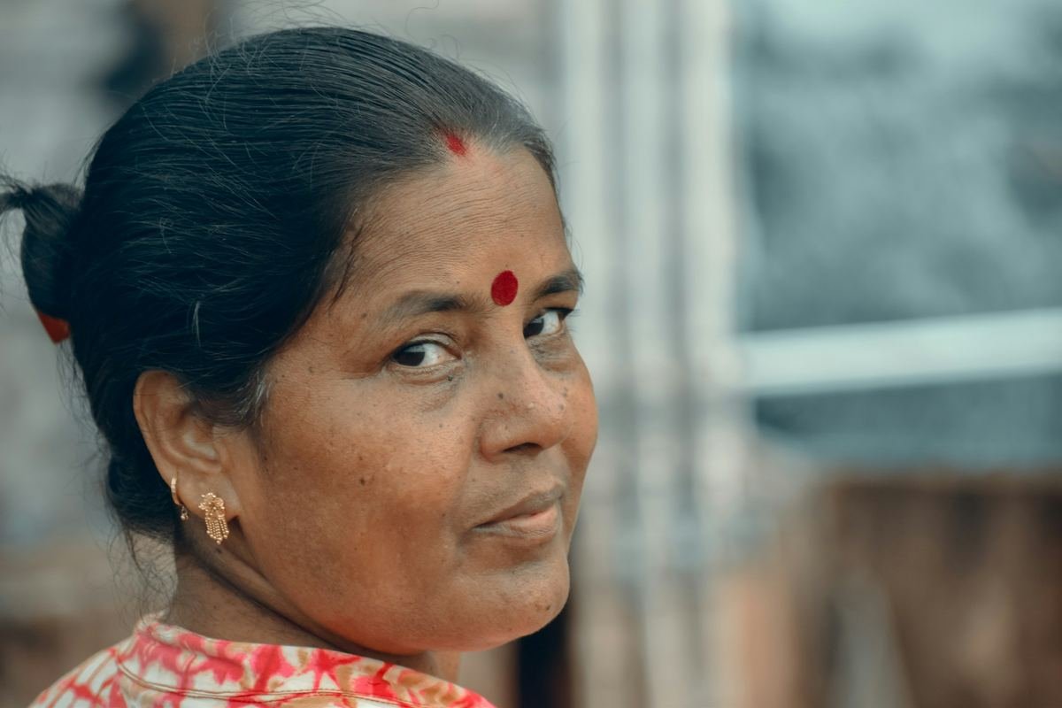 A woman with a red bindi looking over her shoulder.