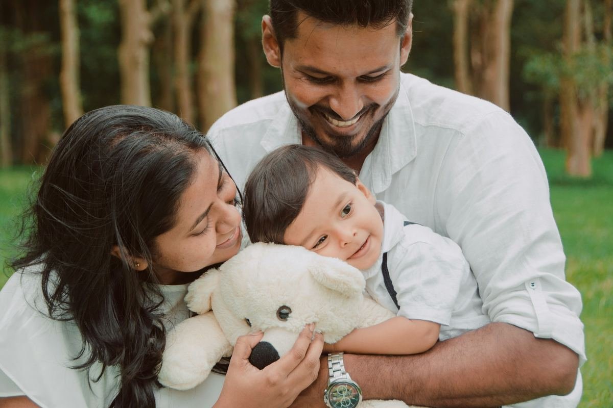 Parents smiling with their baby outdoors.