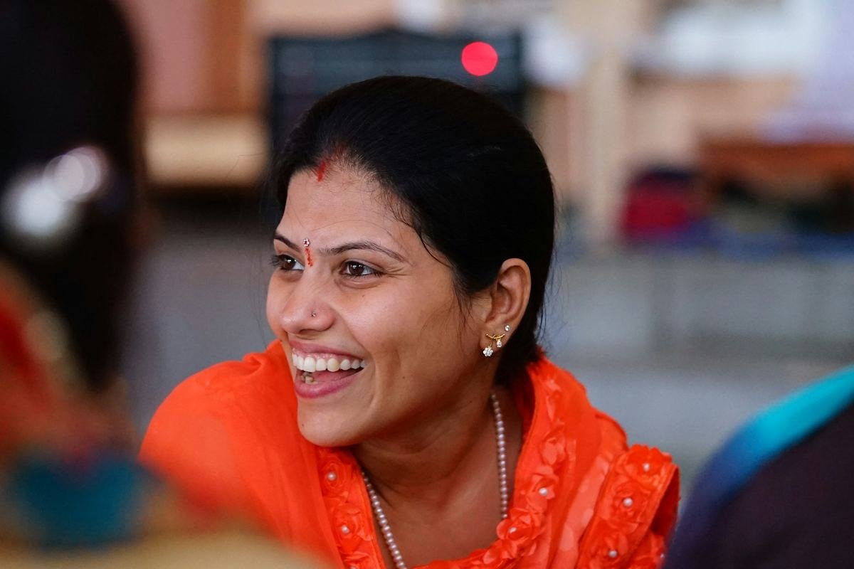 A woman in an orange sari laughing.