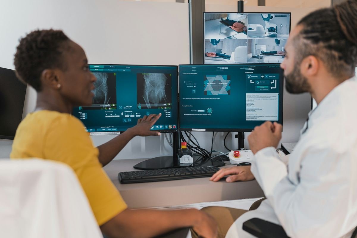 Two clinicians reviewing treatment-planning images on computer screens.