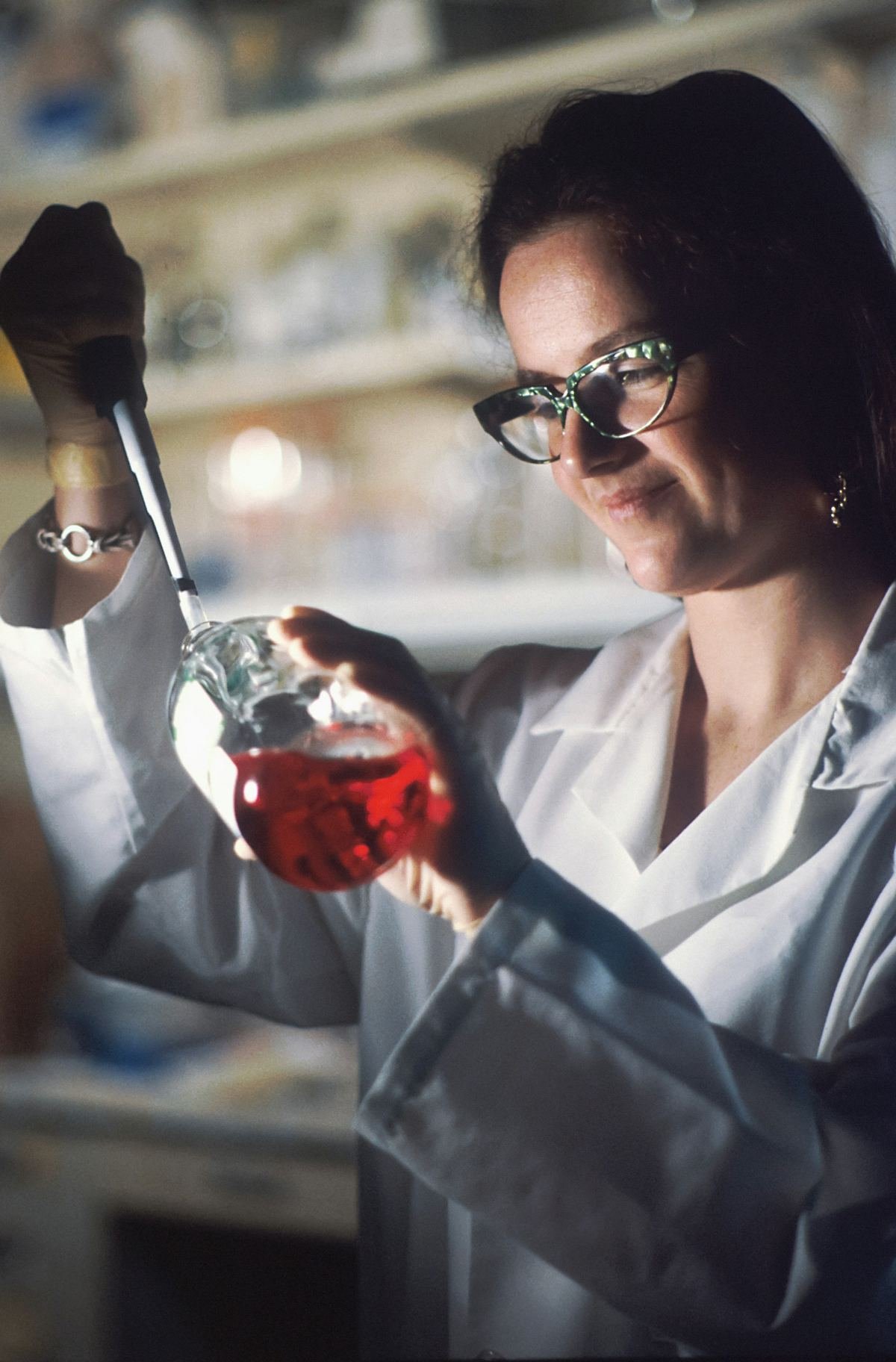 A scientist pipetting culture media into a flask.