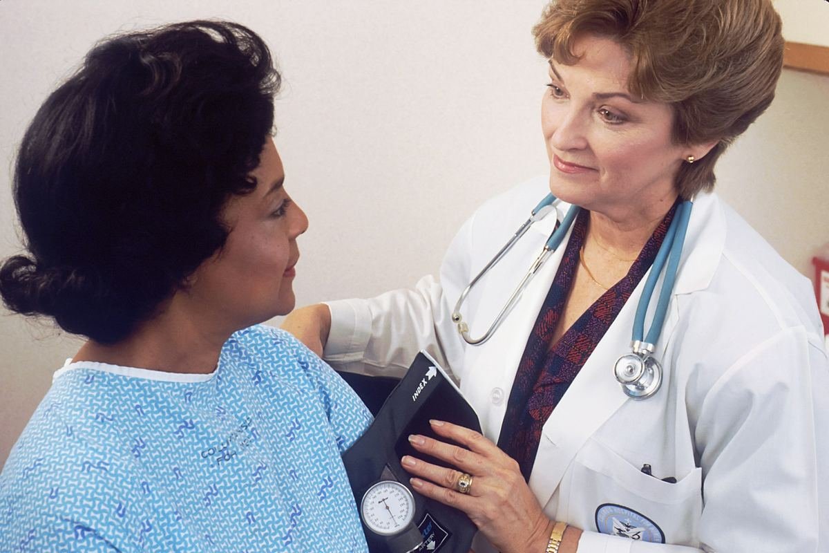 A doctor checking a woman’s blood pressure during a health check.