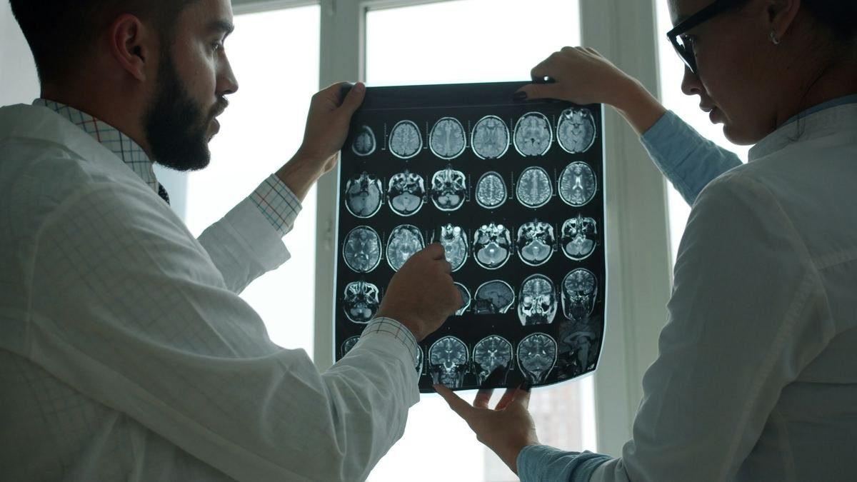 Two clinicians reviewing a series of brain MRI images together.