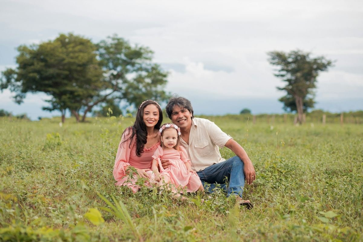 A family sitting together in an open green field.