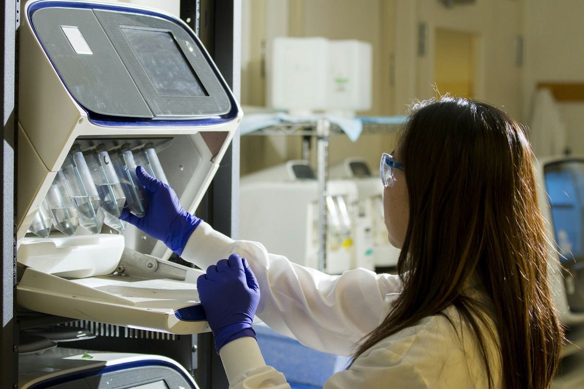 A scientist placing sample tubes into laboratory analysis equipment.