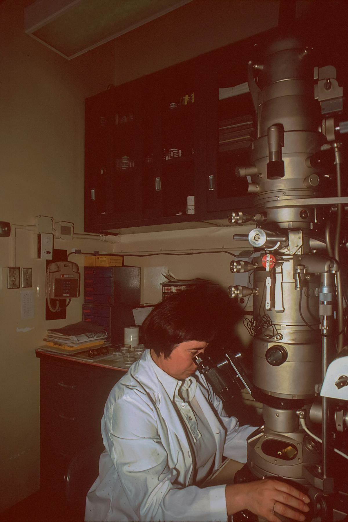 A researcher at a microscope in a laboratory.