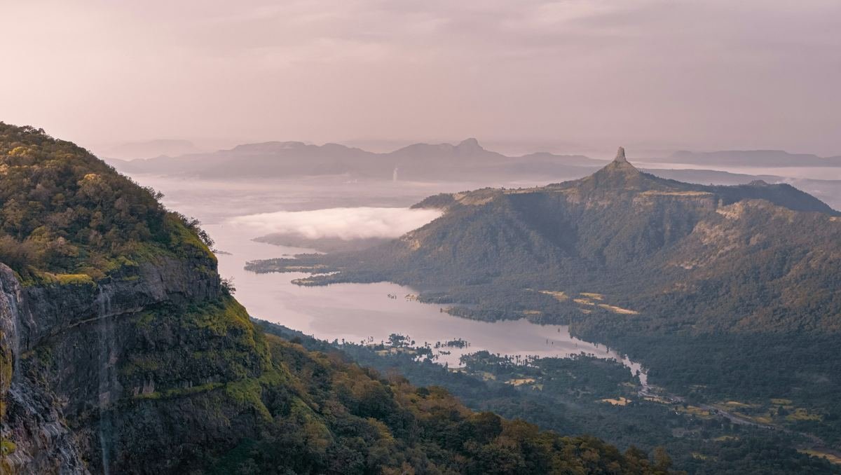 A misty valley with mountains and a lake.