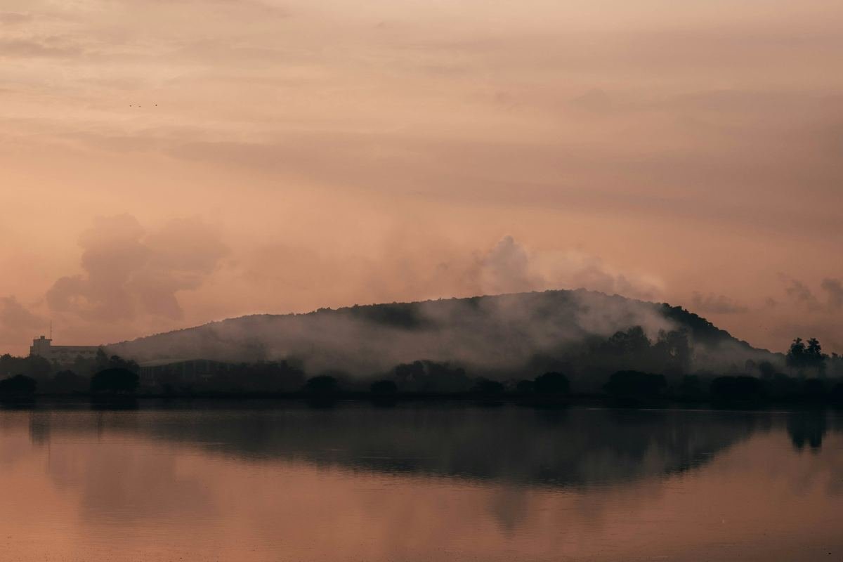 A misty lake at sunrise with a soft pink sky.