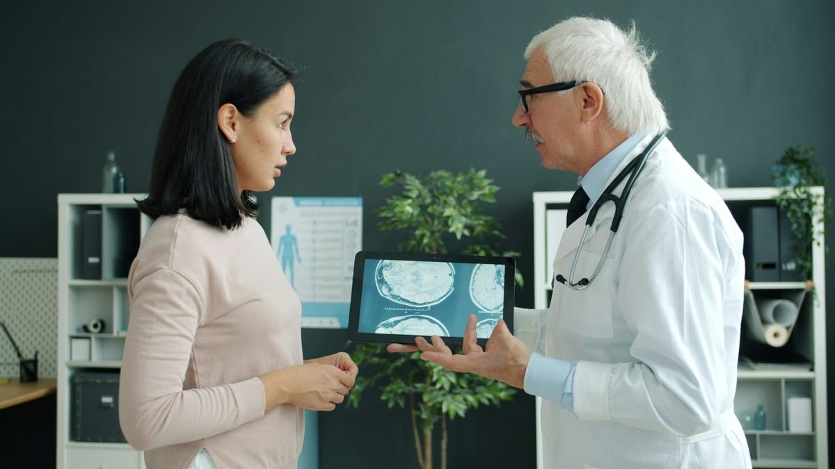 A clinician showing a patient a medical scan on a tablet.