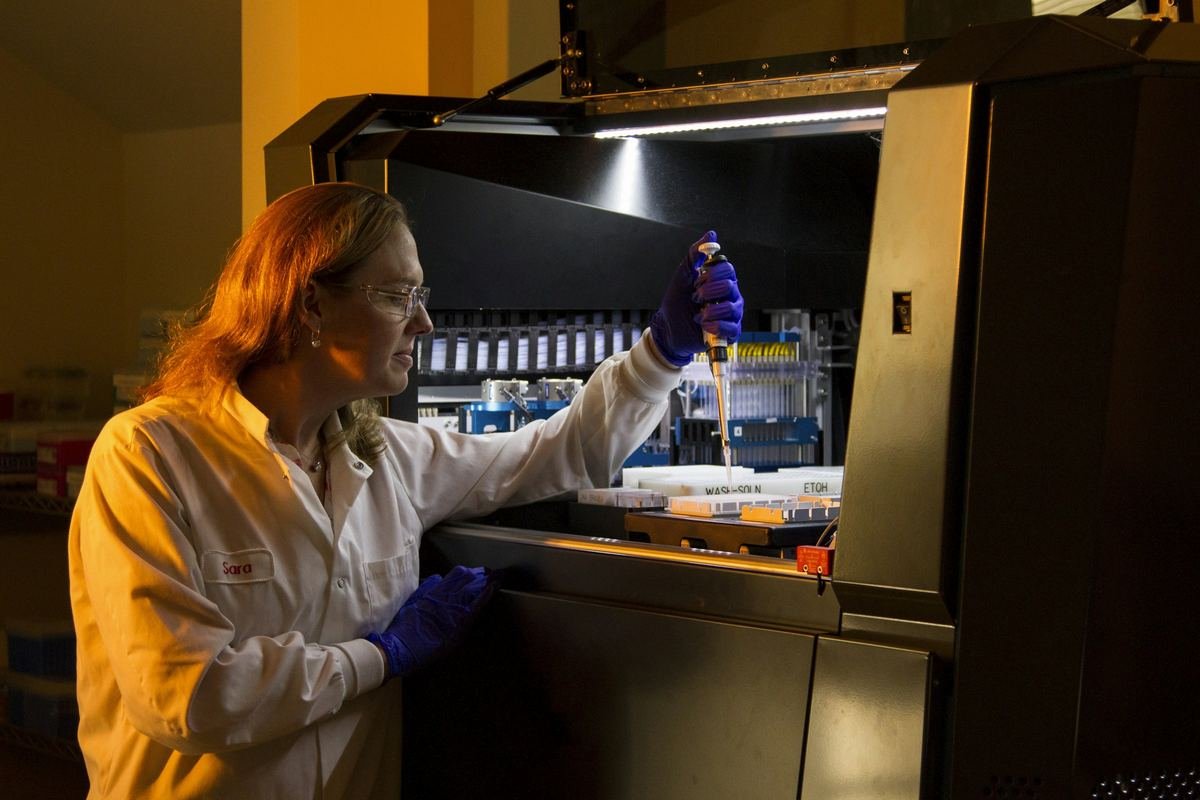 A scientist operating a robotic sample-handling system.