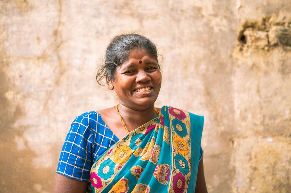 A smiling woman in a colourful sari.