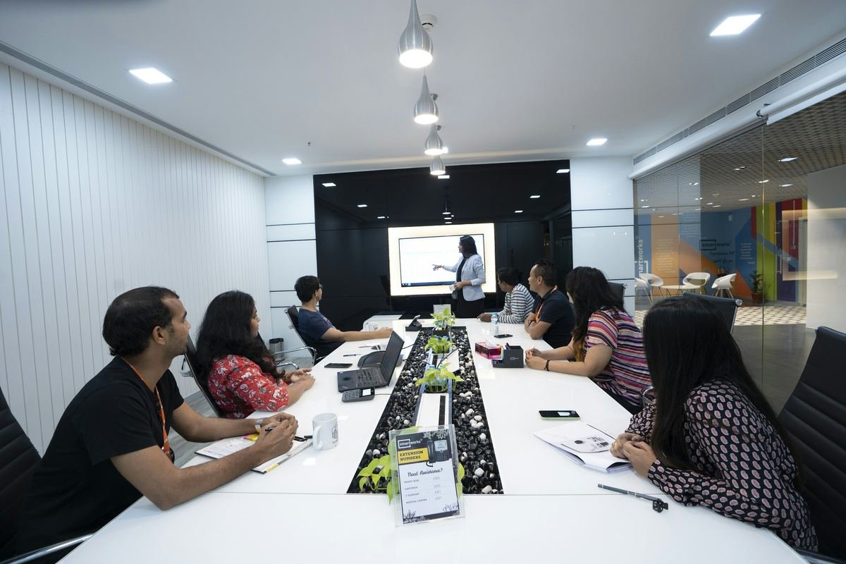 Colleagues around a meeting table listening to a presentation.