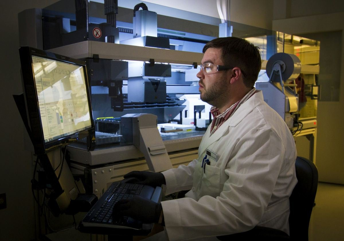 A technician reviewing sequencing data on computer screens.