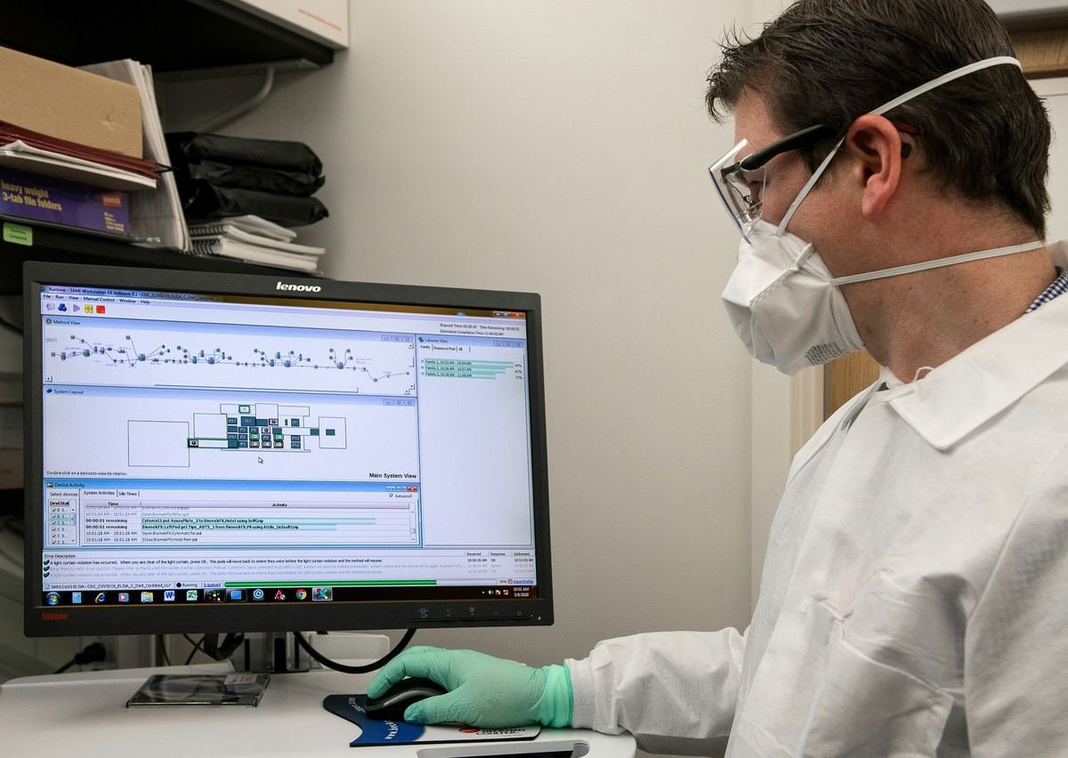 A laboratory scientist reviewing results on a monitor.