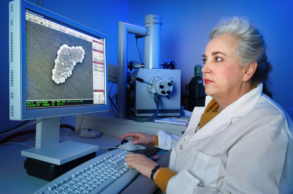 A scientist studying a microscope image on a screen.
